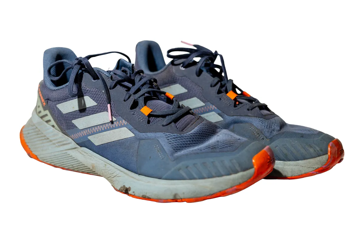 Blue Adidas sneakers before cleaning: grey soles caked with mud, dusty uppers